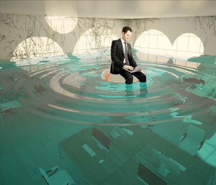 Image of a person with a business suit sitting on a float in a flooded room