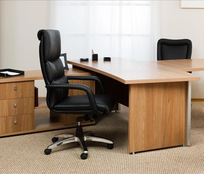 Image of an office with black chairs and wooded desks.